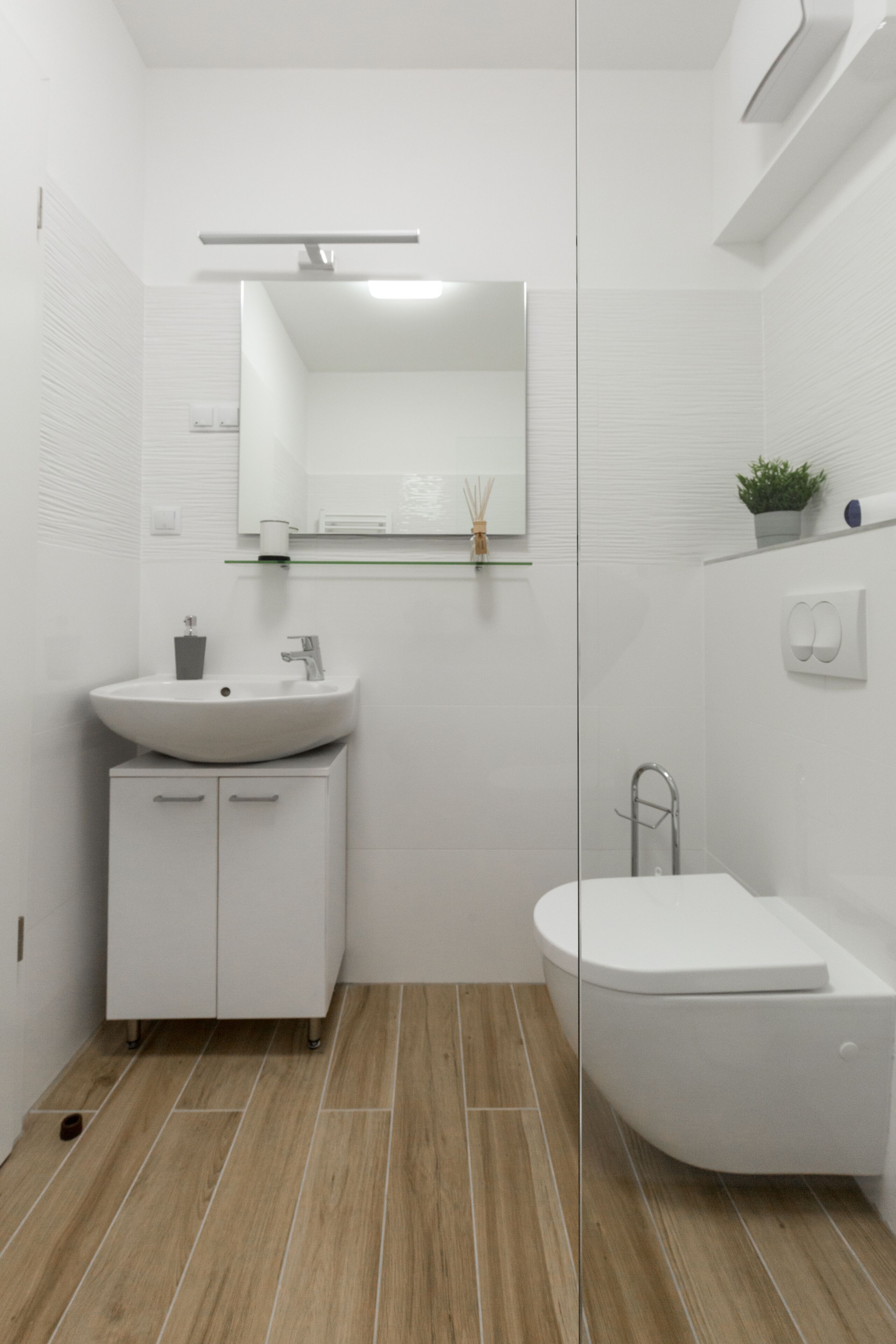 A modern bathroom with a white sink, mirror, and toilet.