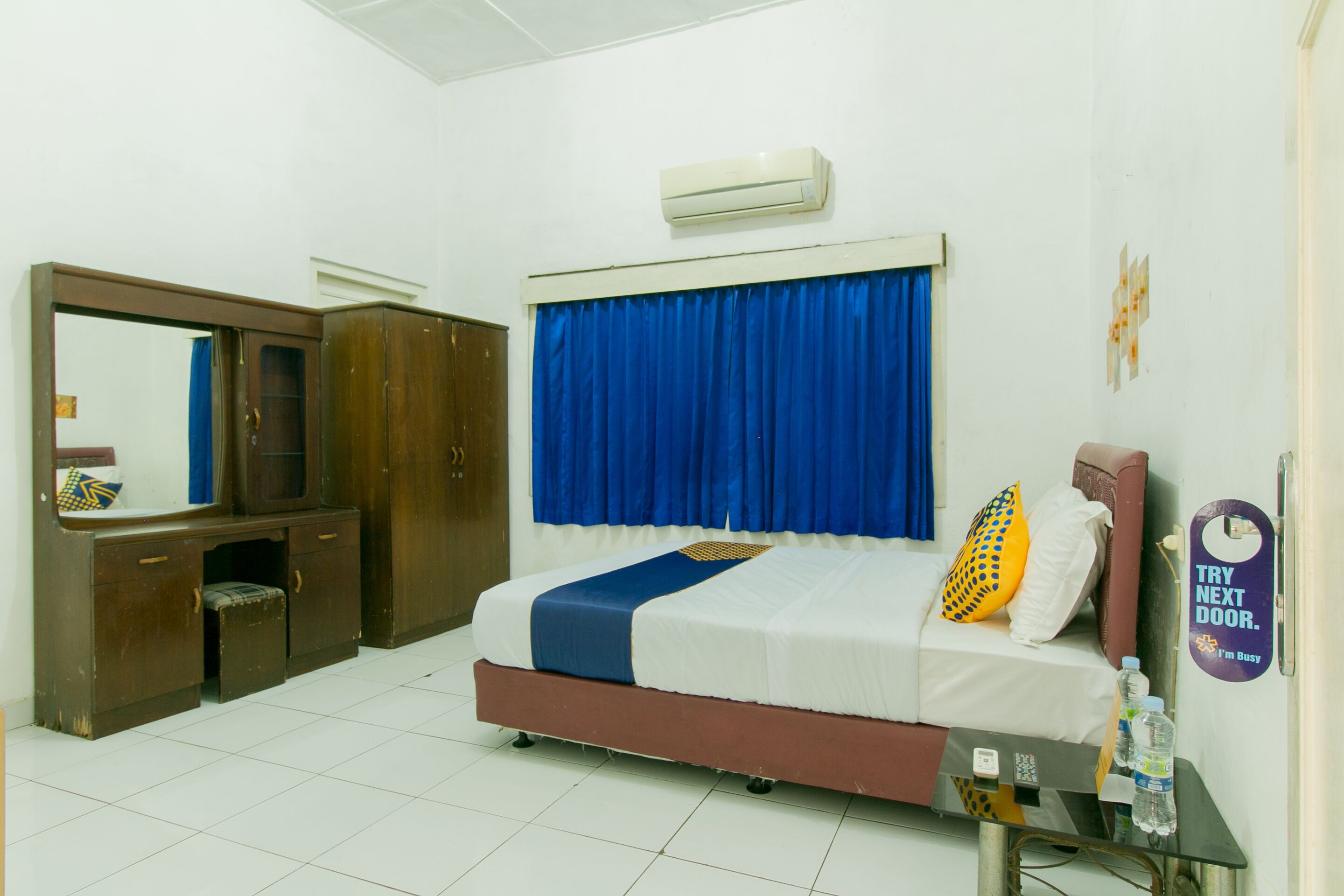 Een hotelkamer met een bed, een bureau, een kledingkast en een airconditioning.