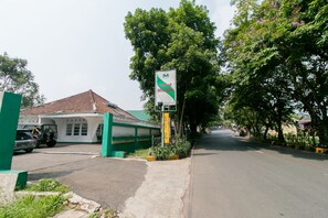 Straßenansicht mit einem Schild für das Hotel Musika, ein grünes Gebäude mit einem Ziegeldach und einem parkenden Fahrzeug.