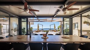A spacious dining area with a large table, black chairs, ceiling fans, and a view of the sea. - Villa Blue Wave , 8 bedrooms, 8 bathrooms,  2 swimming Pool, amazing Sea view  (Kaštel Stari)
