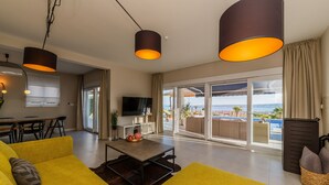 A modern living room with yellow sofas, a coffee table, and a TV. There is a balcony with a view of the sea. - Villa Blue Wave , 8 bedrooms, 8 bathrooms,  2 swimming Pool, amazing Sea view  (Kaštel Stari)