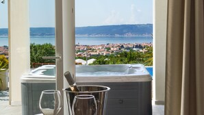 A room with a hot tub, a table with wine glasses, and a view of a coastal town. - Villa Blue Wave , 8 bedrooms, 8 bathrooms,  2 swimming Pool, amazing Sea view  (Kaštel Stari)