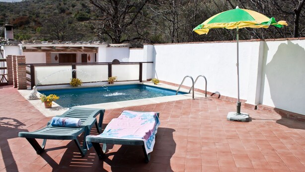 Une piscine avec deux chaises longues et un parasol.