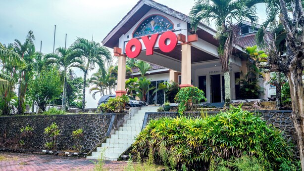 A hotel entrance with a prominent 'OYO' sign, a covered entrance, and a staircase leading up to the main building.