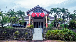 A hotel entrance with a prominent 'OYO' sign, a stone wall, and palm trees.