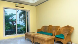 A room with a large sliding glass door leading to a balcony, wicker furniture, and a tiled floor.