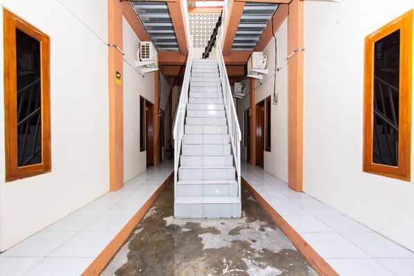 A staircase in a hallway with white walls and wooden accents. - Hotel O Homestay Wak Gobenk (Depok)