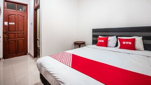 A hotel room with a bed, a wooden door, and a small round table. - OYO 1990 Kost Kuningan Executive Boading House Setiabudi (Jakarta)