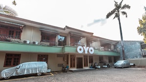 A building with a sign reading "OYO" and covered vehicles parked in front. - OYO 1990 Kost Kuningan Executive Boading House Setiabudi (Jakarta)