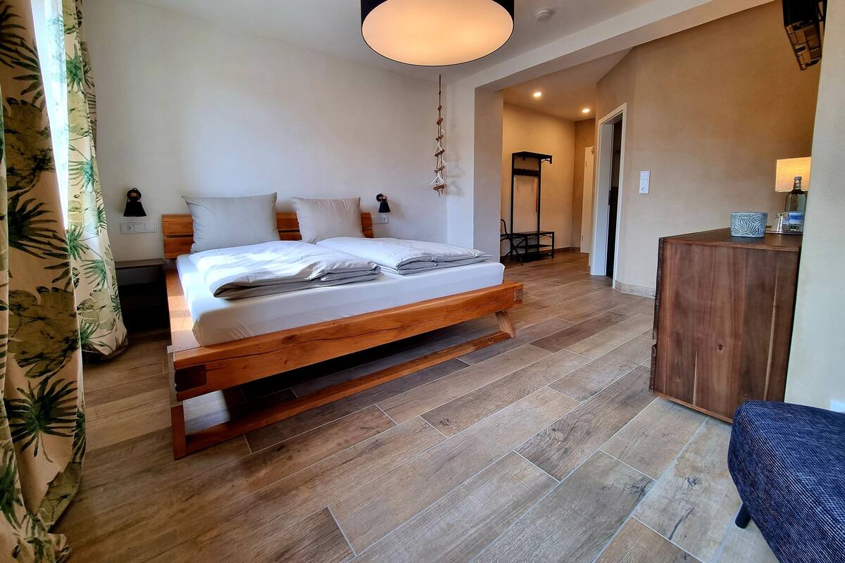 Une chambre à coucher avec un lit en bois, une table de chevet, une commode, un luminaire suspendu, une lampe sur pied, un bureau et une chaise.