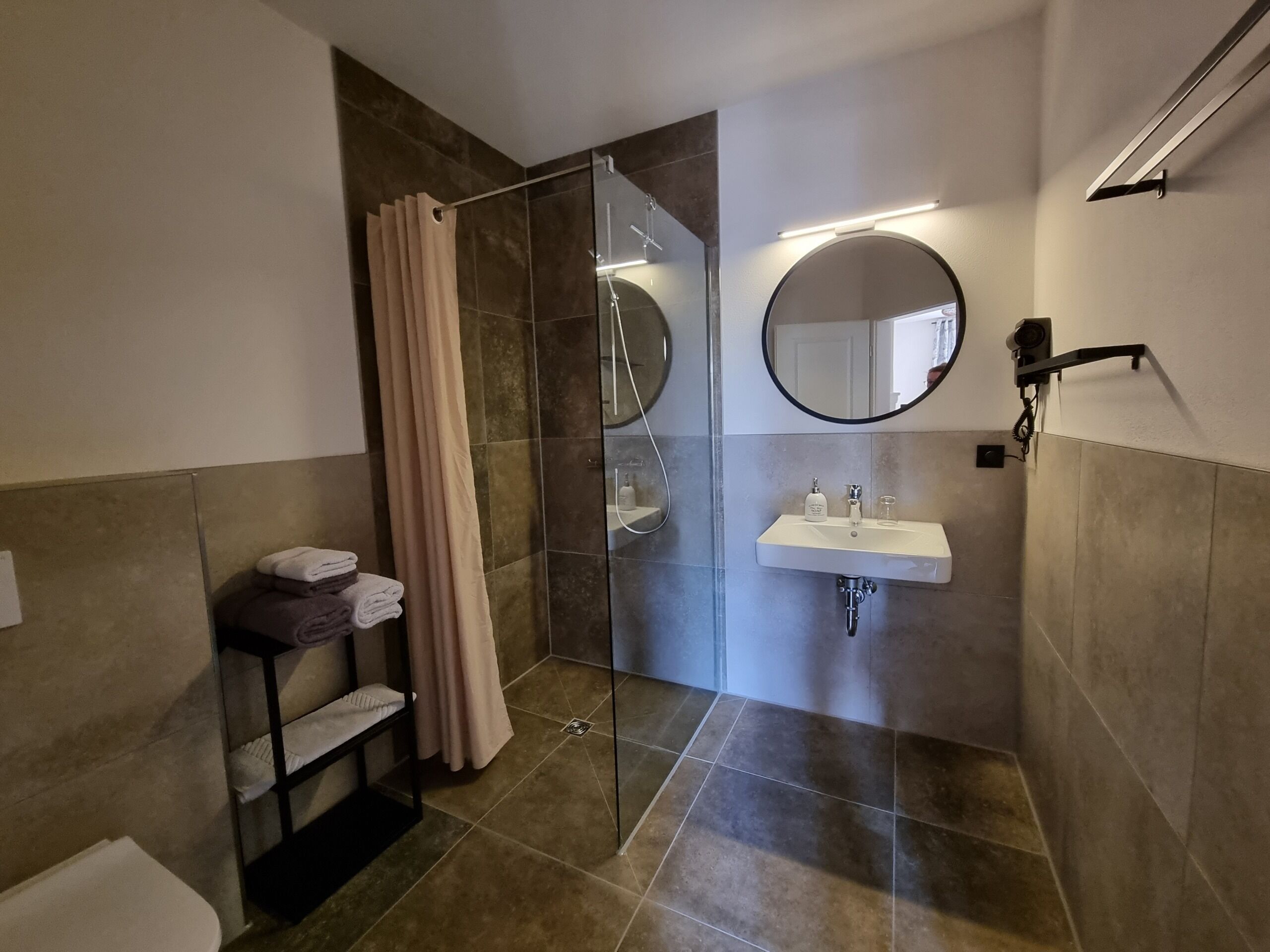 Un baño moderno con cabina de ducha de vidrio, un lavabo blanco y un espejo.