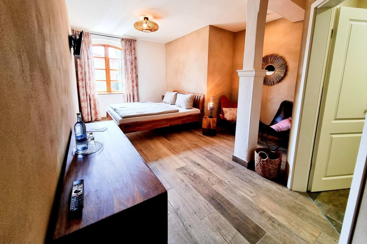 Une chambre à coucher avec un lit en bois, une table de chevet avec une lampe et une fenêtre avec des rideaux.