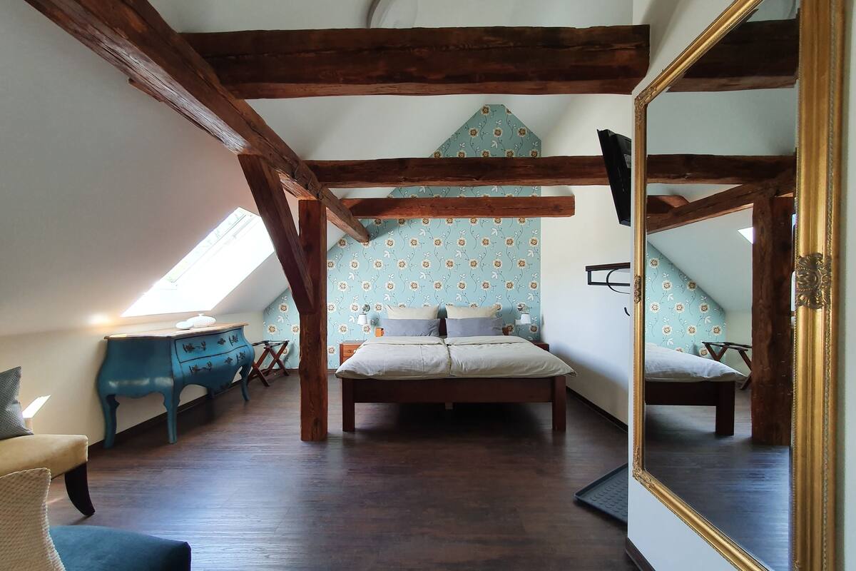 Une chambre à coucher comprenant un lit, une commode, une chaise et un grand miroir.