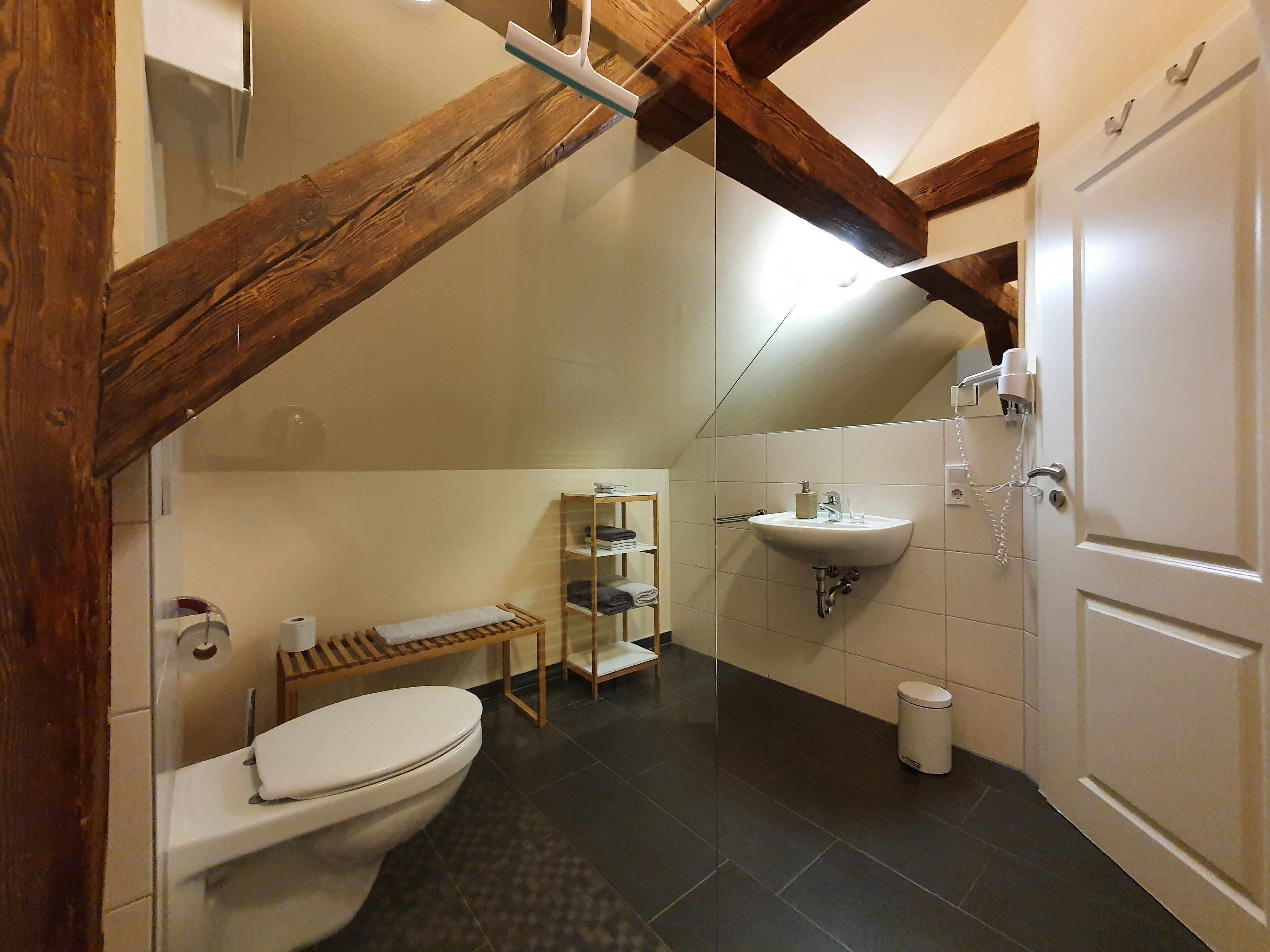 Een kleine badkamer met toilet, wastafel en een plank met handdoeken.