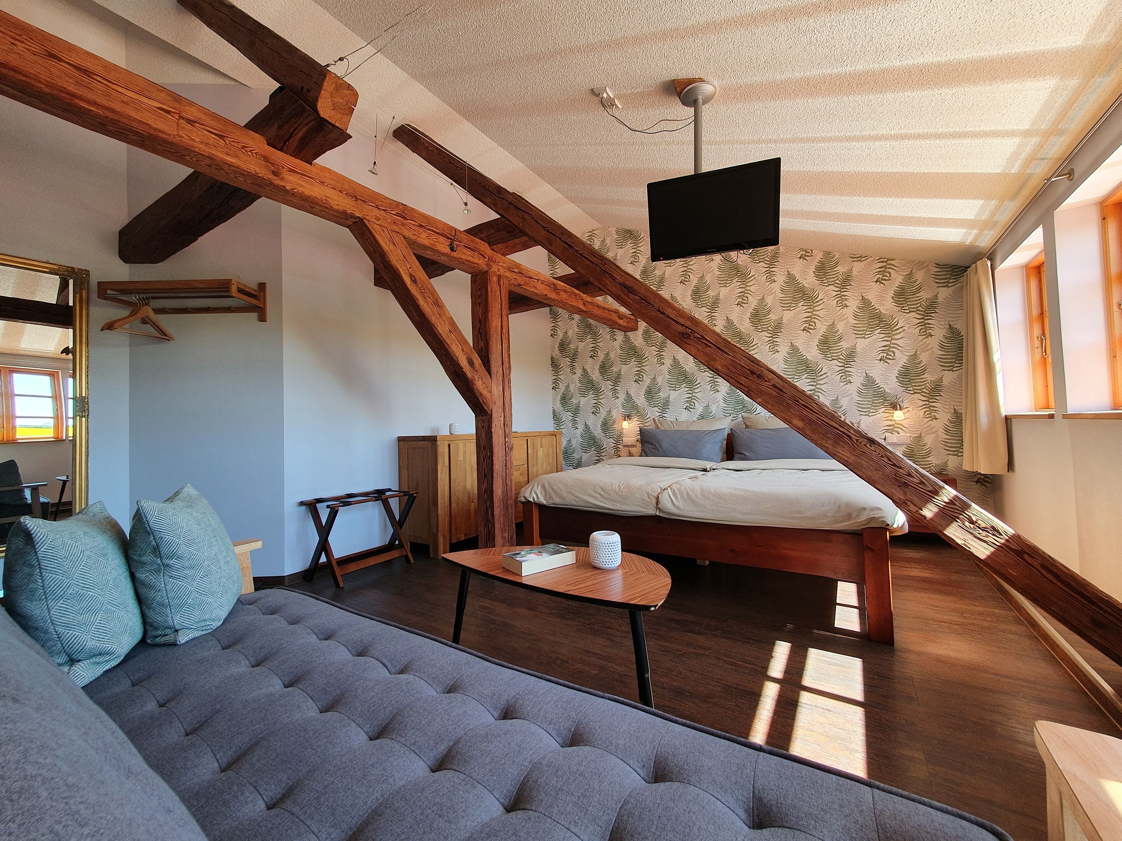 Una habitación acogedora con una cama, un sofá y un televisor en la pared.