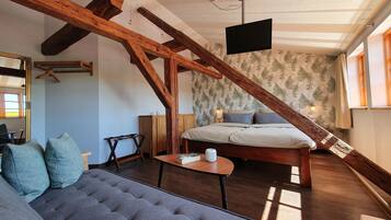 Una habitación acogedora con una cama, un sofá y un televisor en la pared.