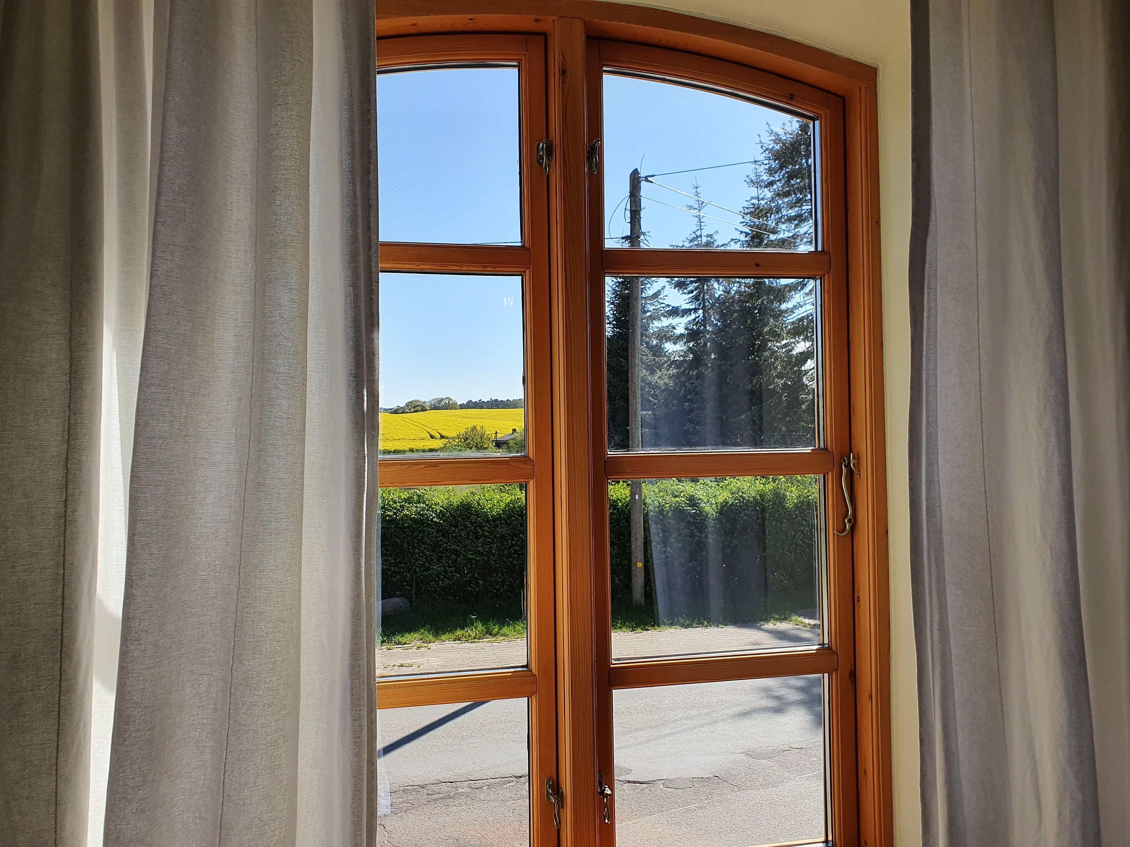Une porte en bois offrant une vue dégagée sur un paysage rural, avec des champs et des arbres.