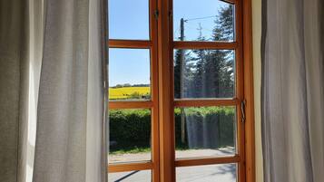 Une porte en bois offrant une vue dégagée sur un paysage rural, avec des champs et des arbres.