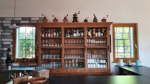 Een keuken met een houten kast vol glaswerk en flessen, een zwart aanrecht en een raam met uitzicht op groen.