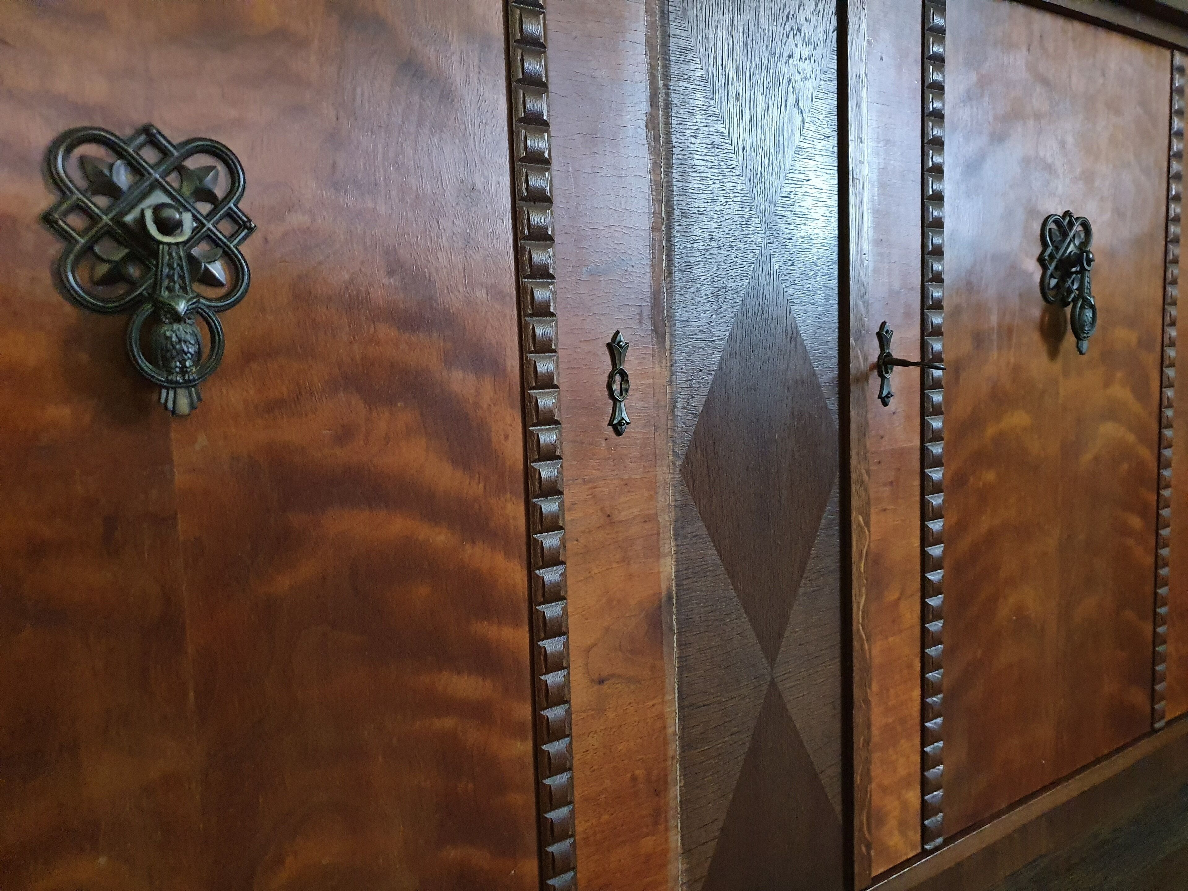 A wooden cabinet with intricate metal handles and decorative patterns.