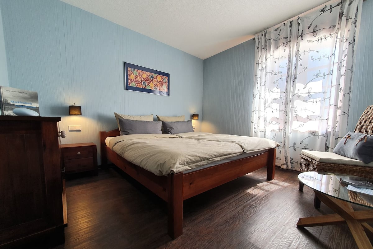 Une chambre à coucher avec un lit en bois, une table de chevet, une commode et une petite table.