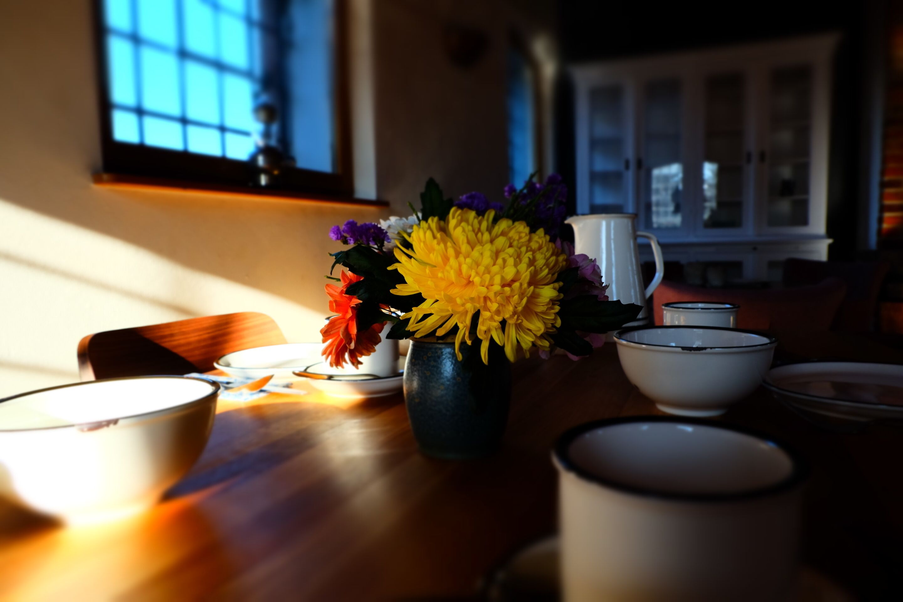 Una mesa de comedor con un jarrón de flores, cuencos y una jofaina.