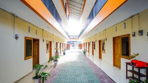 A corridor with a tiled floor, wooden doors, and potted plants. - OYO 1720 A2b Residence (Manado)