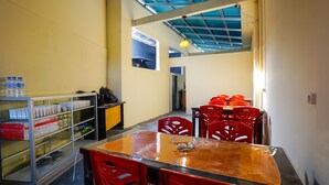 A dining area with a glass display case, red chairs, and a table. - OYO 1720 A2b Residence (Manado)
