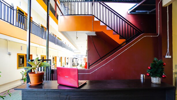 A modern hotel lobby with a staircase, potted plants, and a red laptop on a reception desk. - OYO 1720 A2b Residence (Manado)