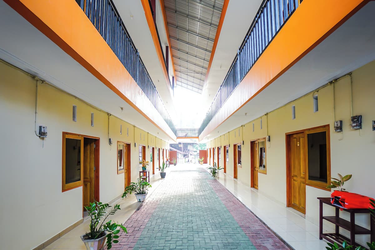 A corridor with a tiled floor, wooden doors, and potted plants.