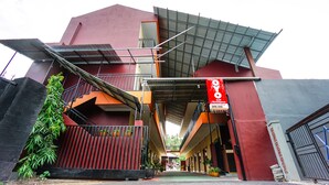 A modern building with a red facade, a covered entrance, and a sign indicating a business or commercial space. - OYO 1720 A2b Residence (Manado)