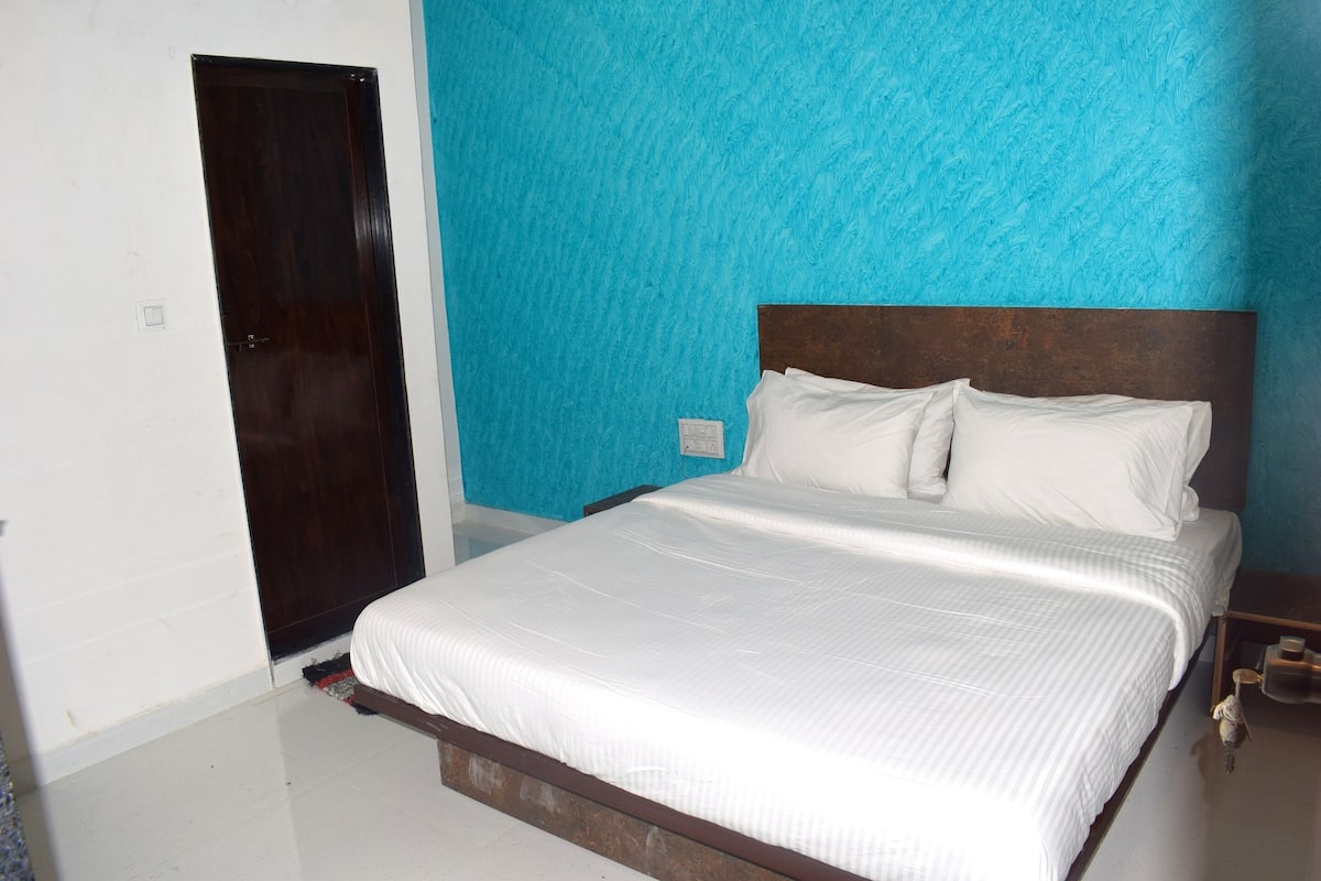 A bedroom with a bed, a wooden headboard, a nightstand, and a door.