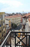 Vista desde un punto alto que domina una calle con edificios, una plaza central y una masa de agua en la distancia.