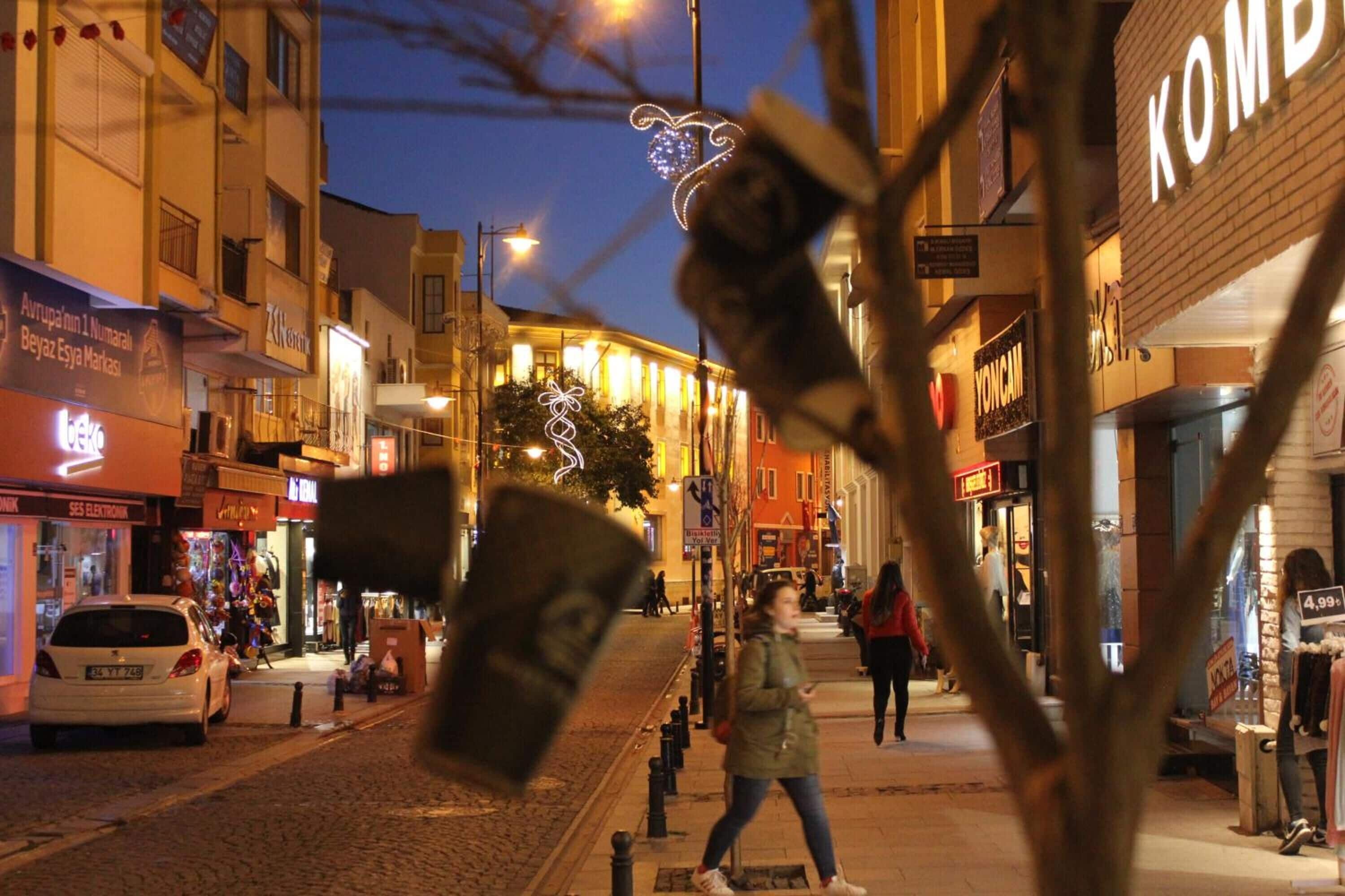 A nighttime street scene with shops and pedestrians.