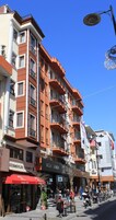 Un edificio de varios pisos con balcones, locales comerciales y un farol.