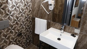 A modern bathroom with a white sink, a toilet, and a shower area. - Degirmenlik Casamia Suite (Çanakkale)