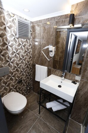 A modern bathroom with a white sink, a toilet, and a shower area. - Degirmenlik Casamia Suite (Çanakkale)