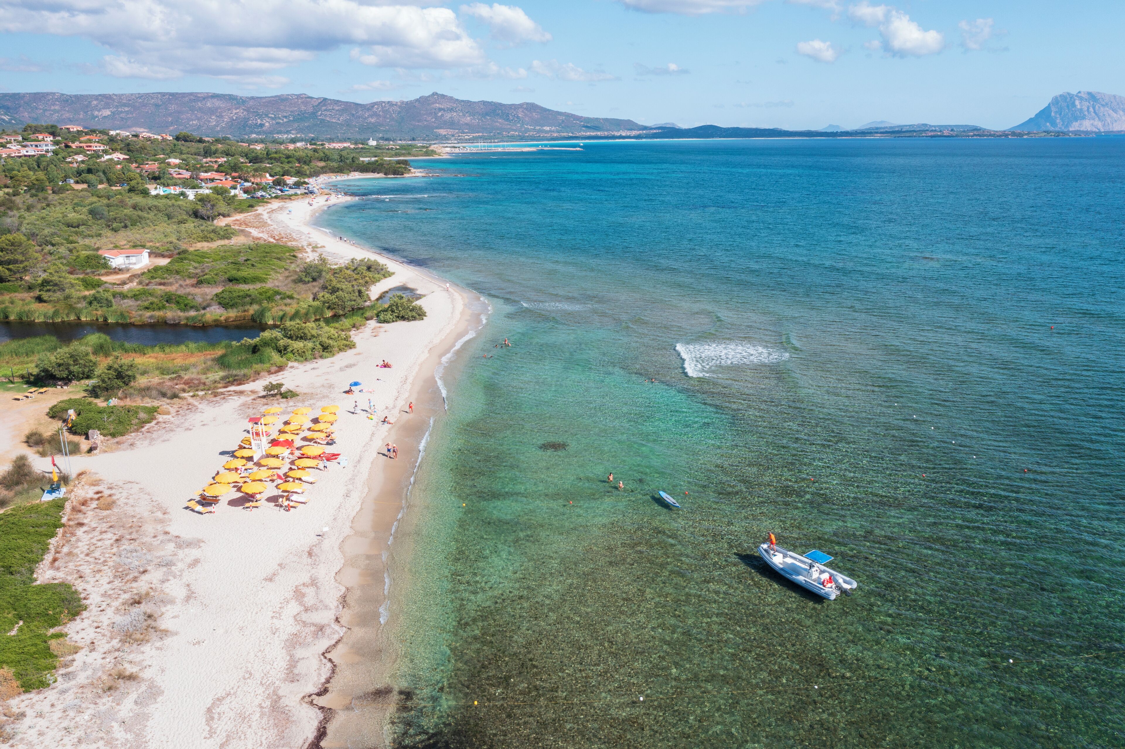 Zona costera con playa, agua cristalina y un bote.