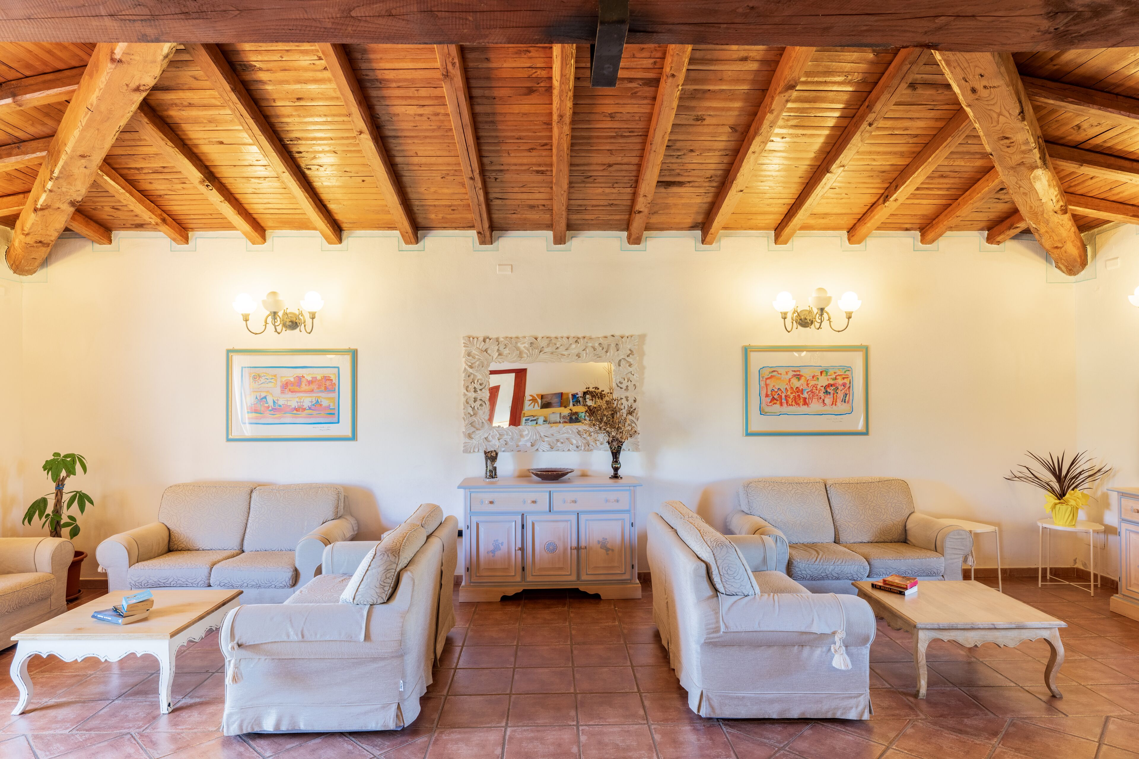 A cozy living room with two sofas, a coffee table, and a cabinet. There are two wall-mounted lamps and a mirror above the cabinet.