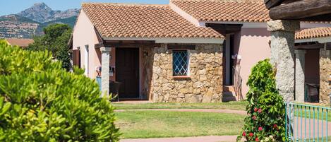 A traditional stone building with a tiled roof, a stone entrance, and a small window with a blue frame.