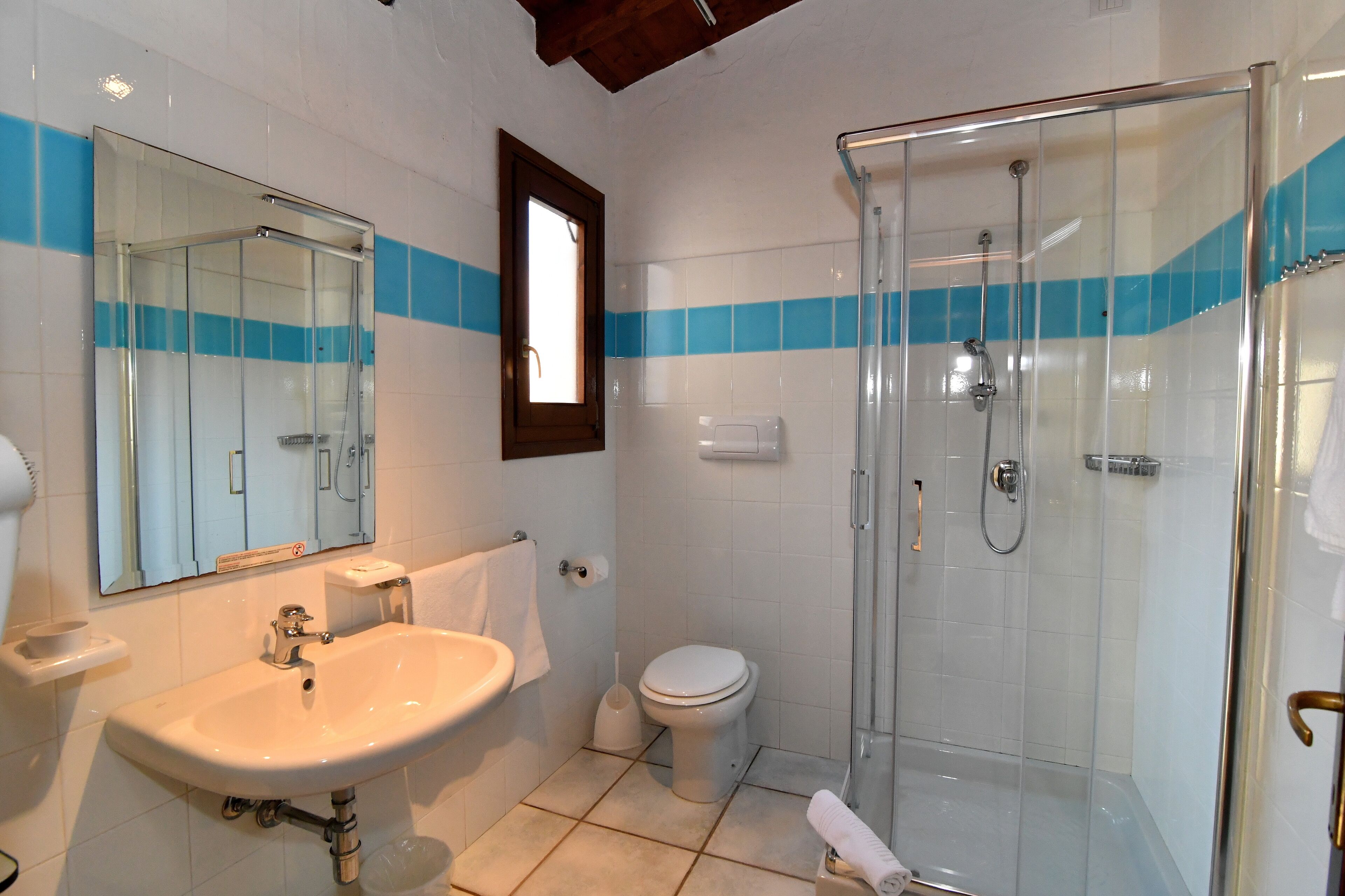 Un bagno con cabina doccia in vetro, lavandino e WC.