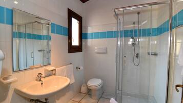 Un bagno con cabina doccia in vetro, lavandino e WC.