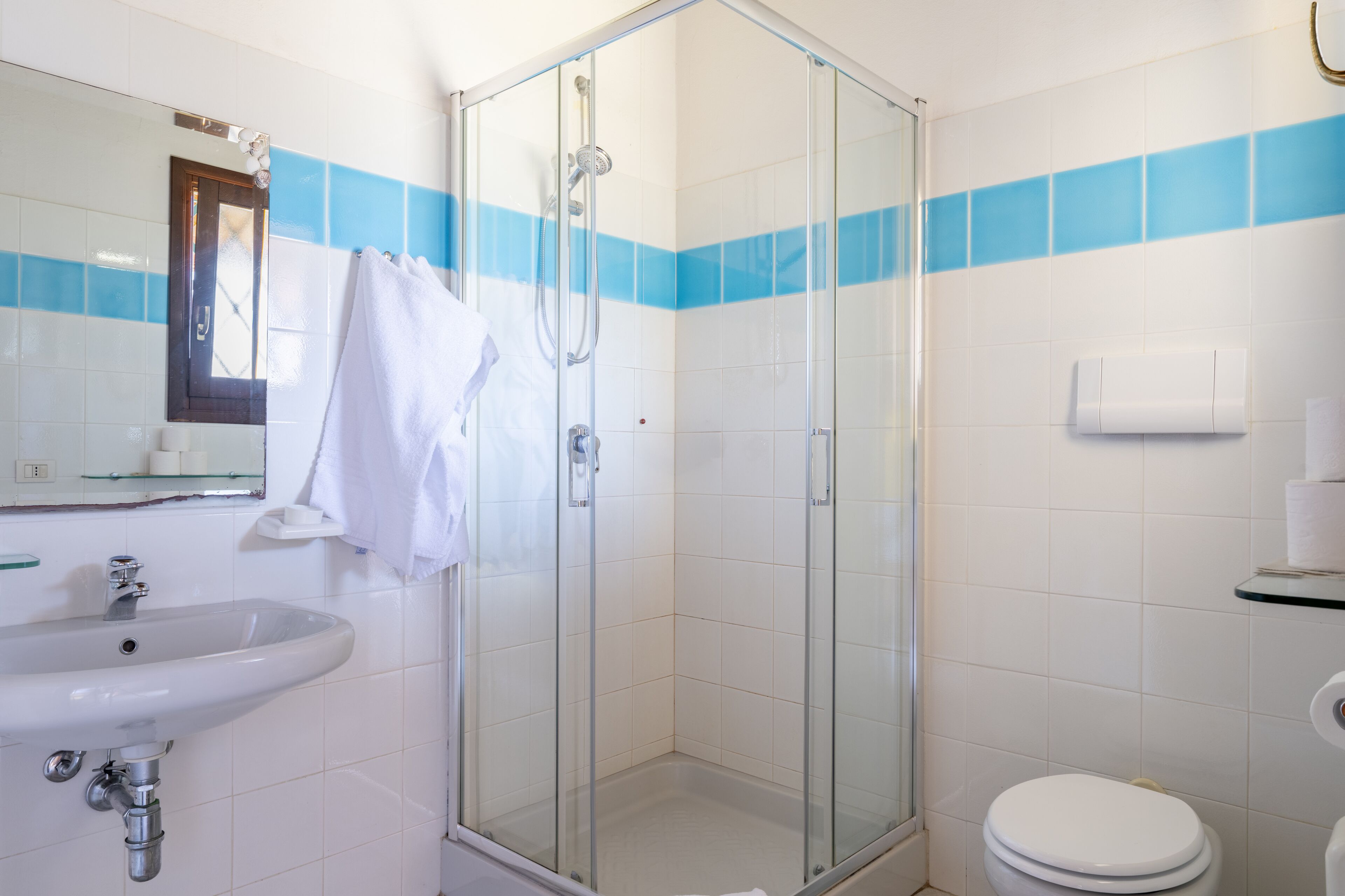 A bathroom with a glass-enclosed shower, a sink, and a toilet.