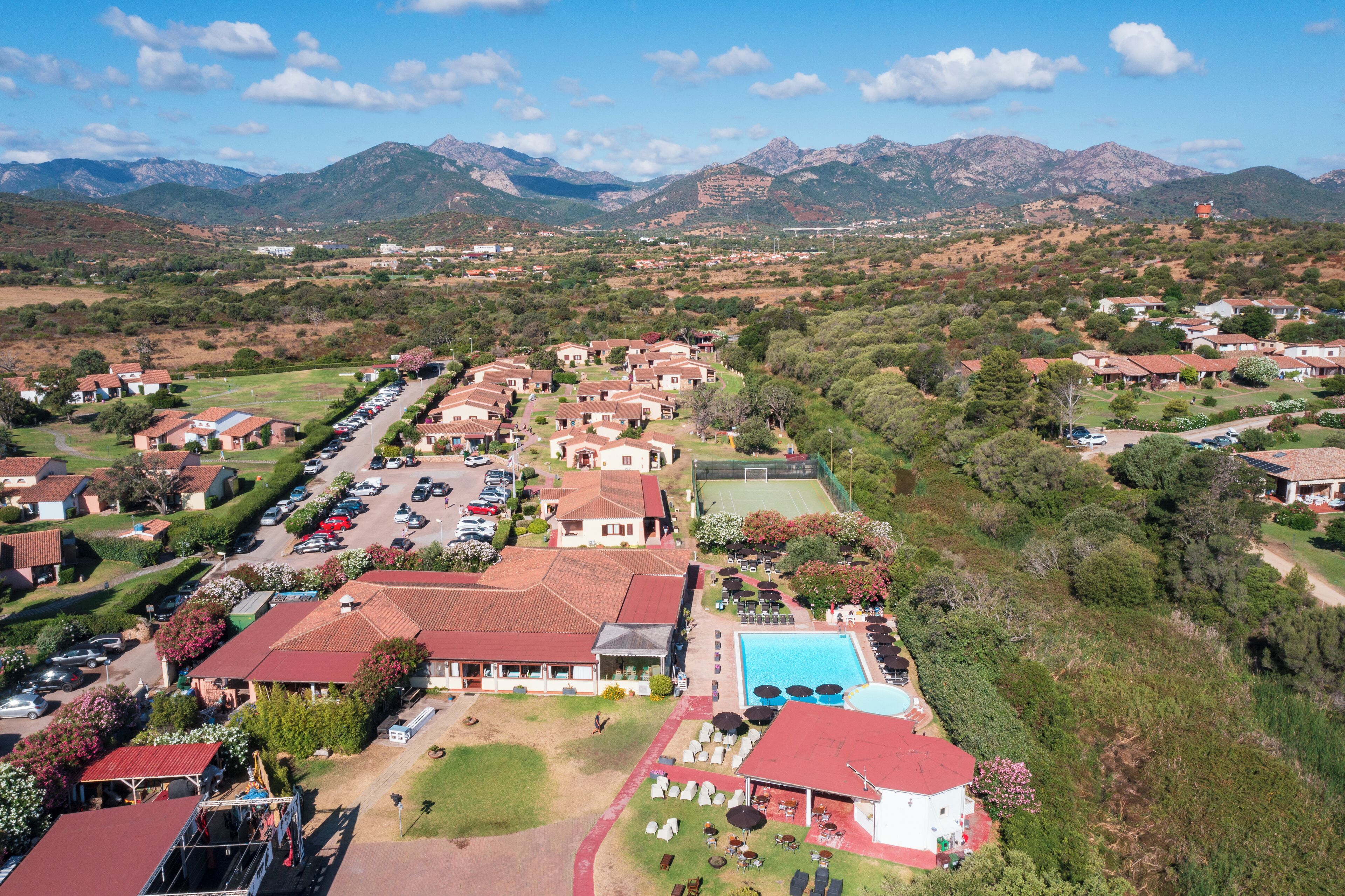 A residential area with houses, a swimming pool, and mountains in the background.