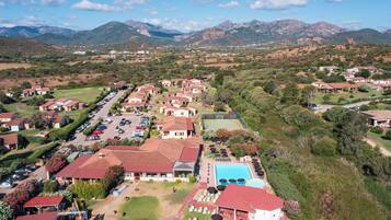 A residential area with houses, a swimming pool, and mountains in the background.
