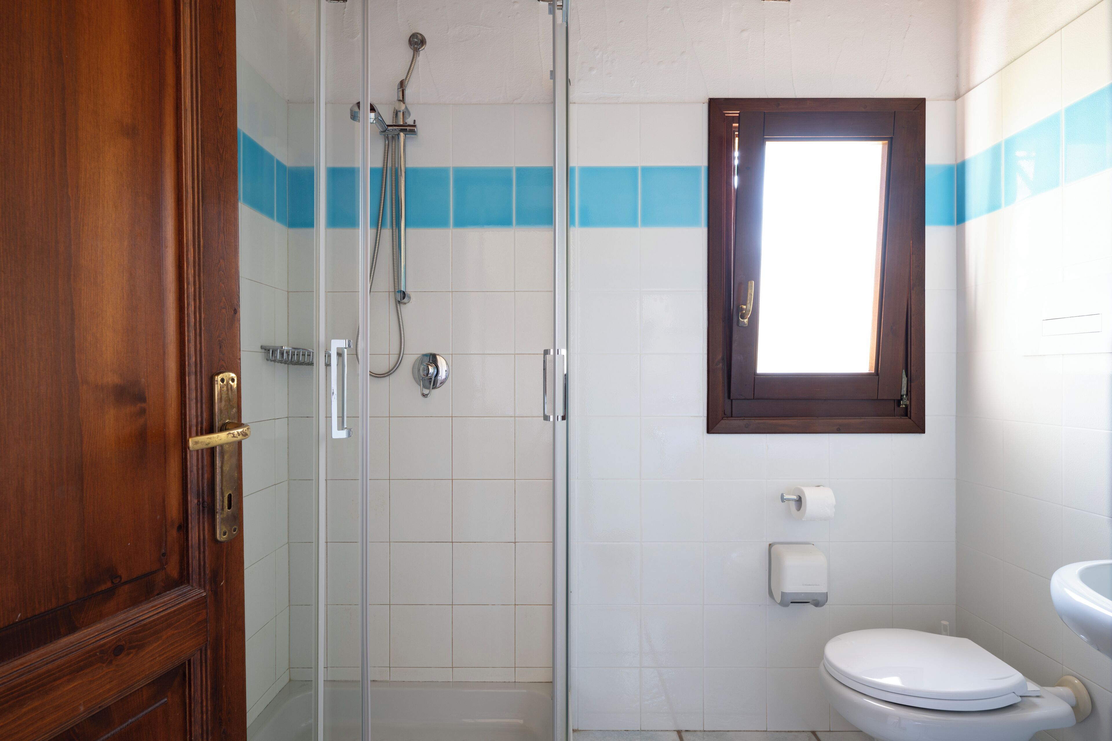 Ein Badezimmer mit Duschkabine aus Glas, Toilette und Waschbecken.