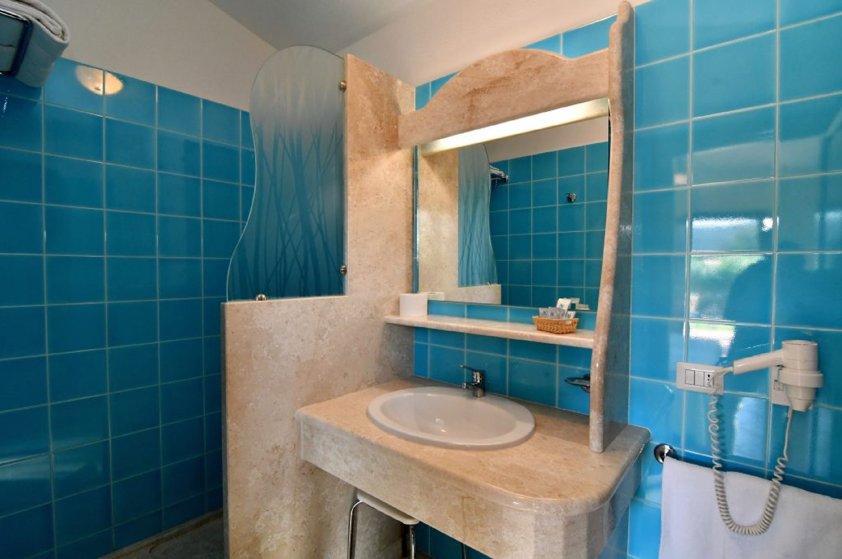 A bathroom with a sink, mirror, and blue tiled walls.