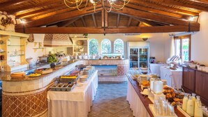 Une cuisine spacieuse avec un haut plafond en bois et un îlot central où sont disposés des aliments.