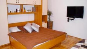 A bedroom with a wooden bed, white walls, and a flat-screen TV mounted on the wall. - Apartments Sikirica 1 (Trogir)