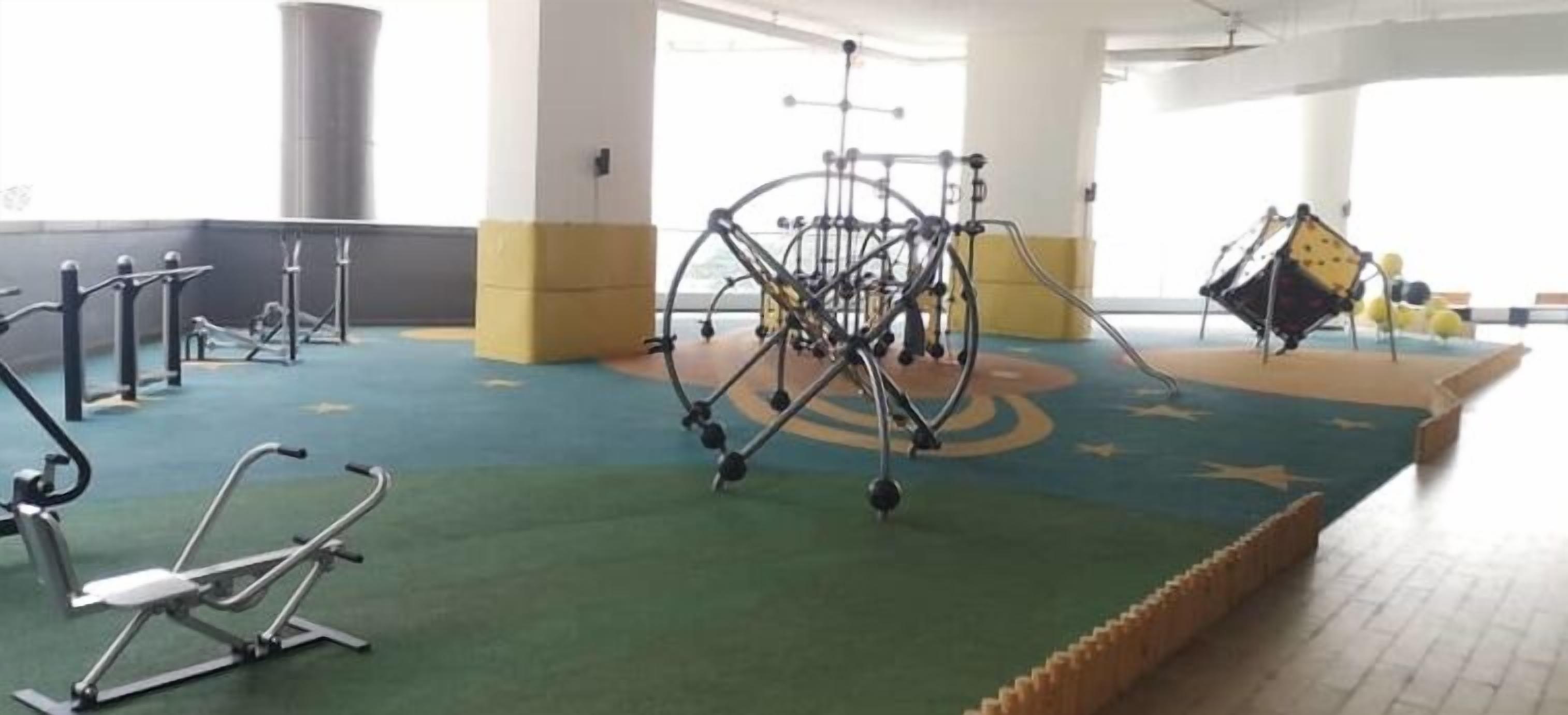 Une salle de sport équipée de divers appareils d’exercice, notamment une machine permettant de travailler différents groupes musculaires, un vélo d’appartement et un appareil de rameur.